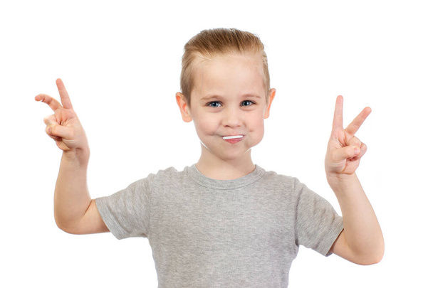 Young smiling caucasian boy with lollipop shows victory sign in mouth isolated on white background - Foto, imagen