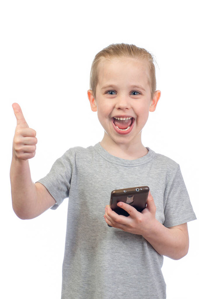 Young smiling caucasian boy with mobile phone shows thumbs up isolated on white background - Foto, immagini