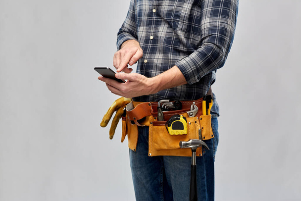 worker or builder with phone and working tools - Foto, immagini
