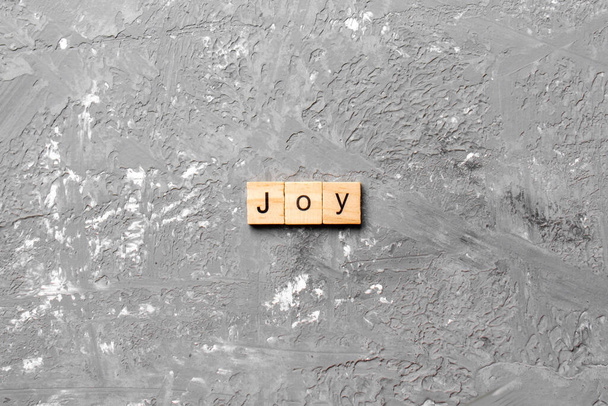 Радісне слово, написане на дерев'яному блоці. Текст радості на цементному столі для вашого бажання, концепція
. - Фото, зображення