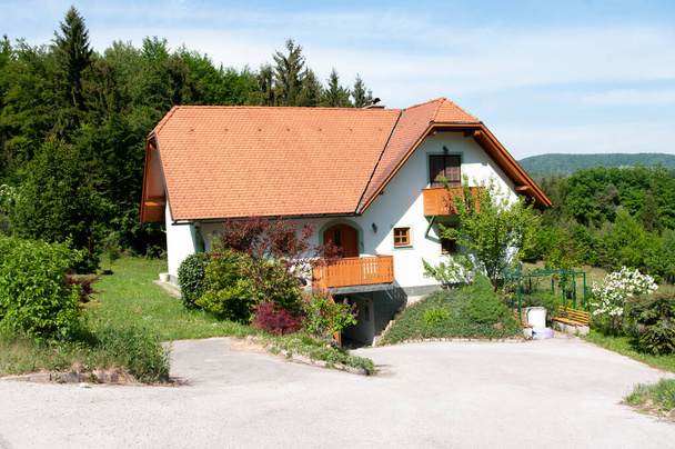 Casas com telhado de azulejos vermelhos, em uma aldeia, tempo de primavera. Construindo sobre a natureza com a floresta ao redor
. - Foto, Imagem