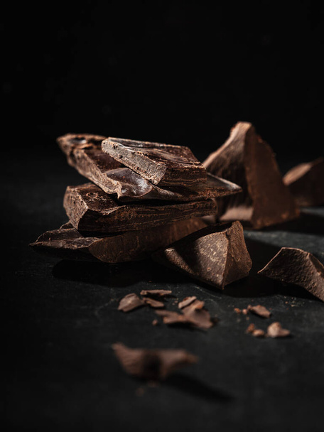 broken bar of dark chocolate on a dark background - Foto, Imagem