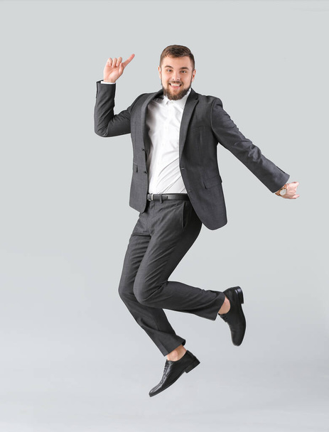 Handsome young businessman dancing against light background - Foto, immagini