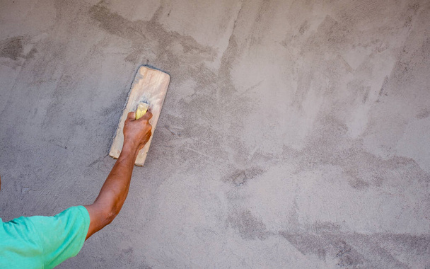 家の建設、作業のアイデア、住宅建設のための壁を漆喰するために石膏のトロールを使用して労働者のクローズアップ. - 写真・画像