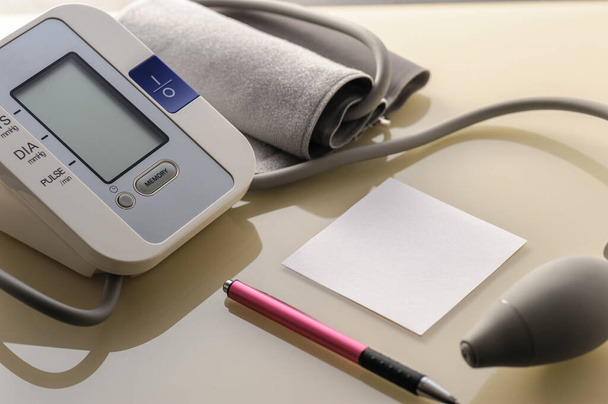 monitor krevního tlaku s listem pro poznámky na lehkém stolku - Fotografie, Obrázek