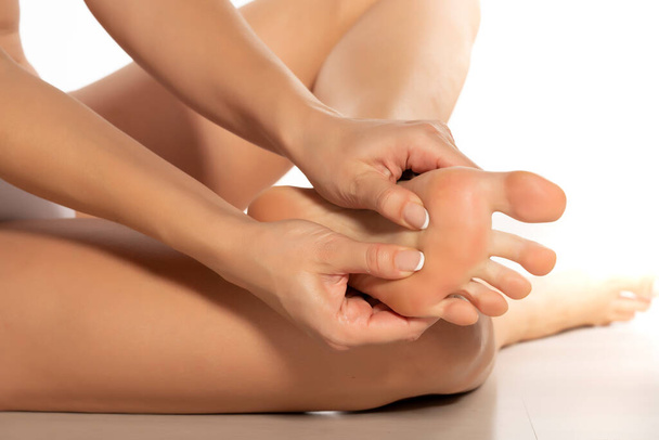 woman massaging her painful foot on white background - Fotó, kép