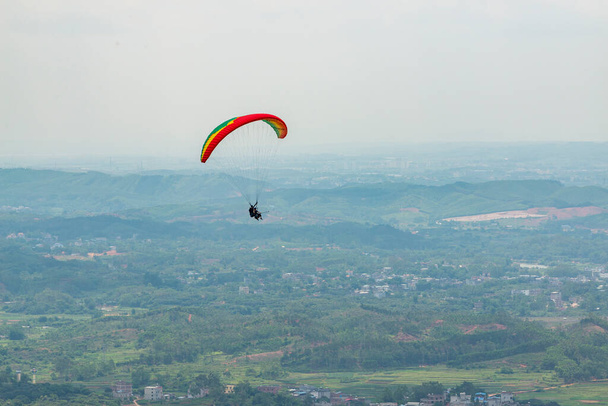 Outdoor city green hill scenery and paragliding - Photo, Image
