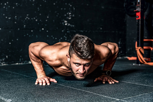 Strong sweaty fit young toned muscular fitness man with big muscles push ups workout cross training on the gym floor  - Valokuva, kuva