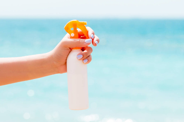 Image recadrée de la main d'une femme tenant un spray solaire sur la plage
. - Photo, image