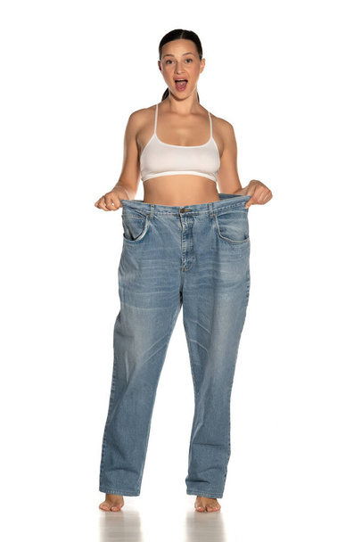 Young slim happy woman in big size pants on white background - Фото, зображення