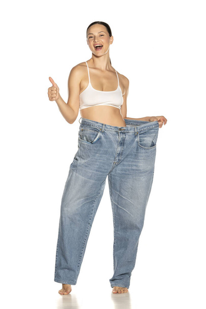 Mujer delgada joven en pantalones de gran tamaño mostrando los pulgares hacia arriba
 - Foto, Imagen