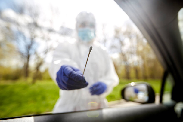healthcare worker making coronavirus test at car - Foto, Imagem