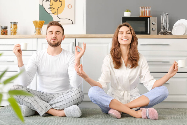 Happy young couple meditating in kitchen - Foto, Imagen