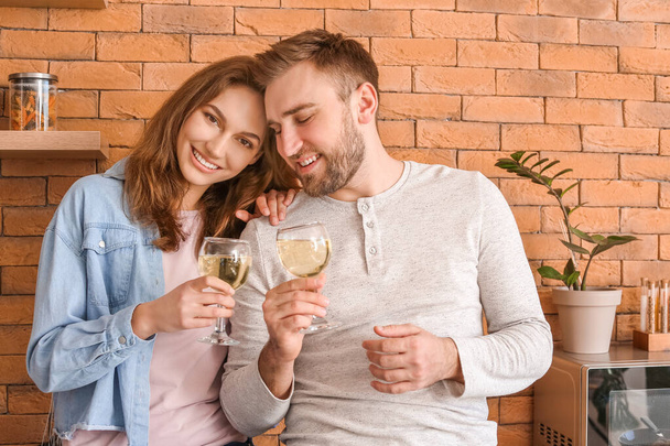 Feliz joven pareja bebiendo vino en la cocina
 - Foto, imagen