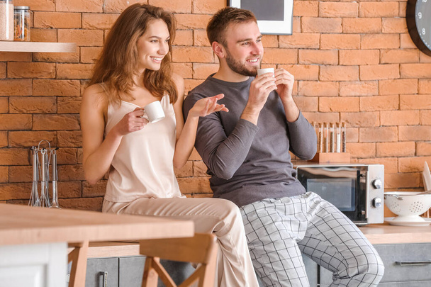 Morning of happy young couple drinking coffee in kitchen - Foto, Bild