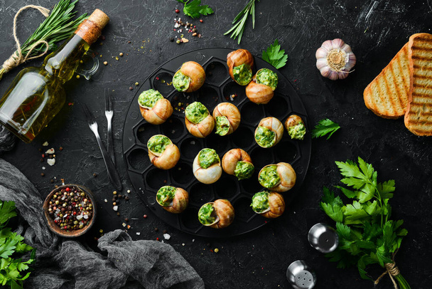 French food. Baked snails with pesto sauce on a black stone background. Top view. Free space for your text. - Foto, immagini
