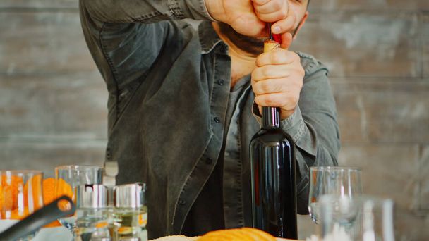 Κοντινό πλάνο του ανθρώπου που ανοίγει ένα μπουκάλι κόκκινο κρασί - Φωτογραφία, εικόνα