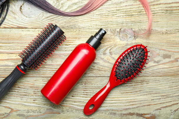 Haarspray mit Bürsten und Strähne auf Holzgrund - Foto, Bild
