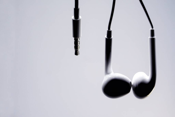 Σιλουέτα λευκού ακουστικού με λευκό φόντο, αντιγραφή χώρου. - Φωτογραφία, εικόνα