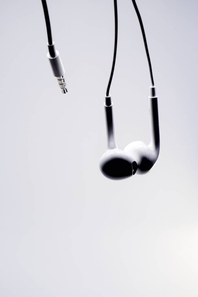 Σιλουέτα λευκού ακουστικού με λευκό φόντο, αντιγραφή χώρου. - Φωτογραφία, εικόνα