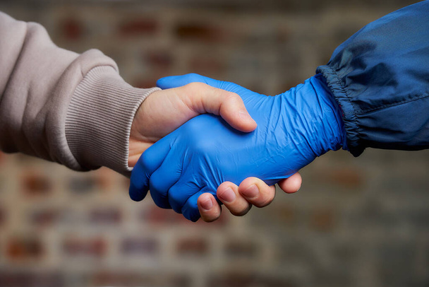 Potřesení rukou. Žena potřást rukou v jednorázové lékařské rukavici s mužem, aby se zabránilo šíření koronaviru (COVID-19). Dva přátelé se potkají na ulici - Fotografie, Obrázek