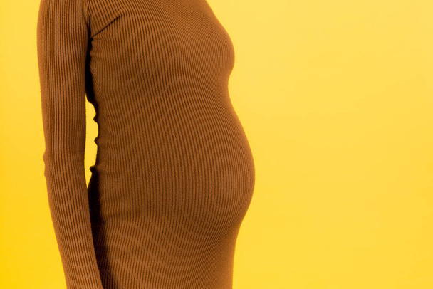 青い背景で妊婦の腹部を閉じてください。女の子は白い下着を着ている。妊娠の概念。スペースのコピー. - 写真・画像