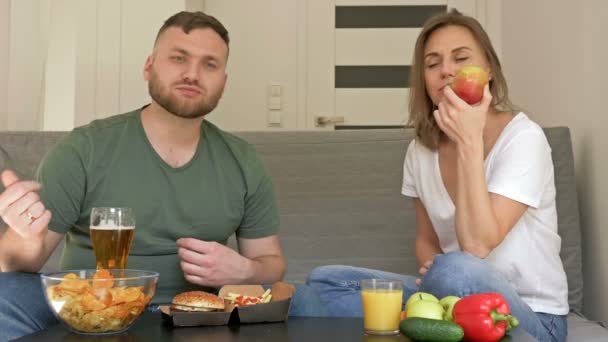 A fiatal párnak más étkezési szokásai vannak. A férj boldogan eszik gyorskaját, a feleség vegetáriánus. Egészséges és egészségtelen táplálkozás. - Felvétel, videó