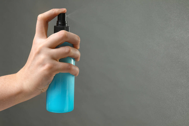 Mão feminina com spray de cabelo em fundo cinza
 - Foto, Imagem