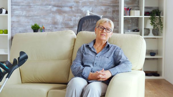 Самотня стара жінка сидить на дивані
 - Фото, зображення