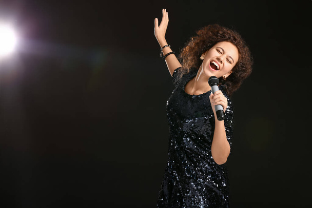 Young African-American woman singing on dark background - Photo, Image