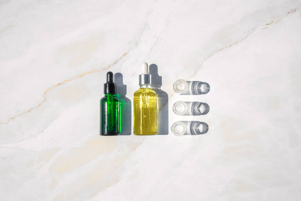 Aceite homeopático, suero y botellas con plantas sobre fondo de mármol
 - Foto, imagen