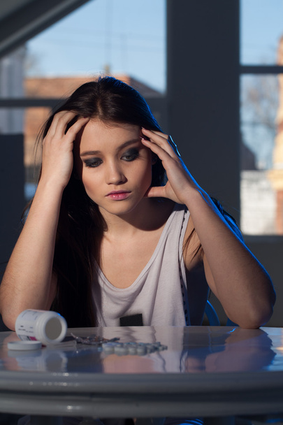 fiatal lány ült az asztalnál egy szétszórt tabletta - Fotó, kép