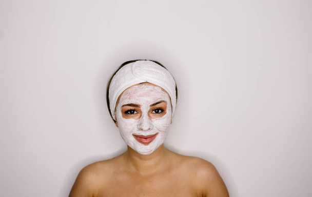 Hermosa mujer con máscara facial sobre fondo blanco
 - Foto, Imagen