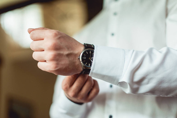 Geschäftsmann, der die Uhrzeit an seiner Armbanduhr überprüft, Mann, der die Uhr an der Hand hält, Bräutigam, der morgens vor der Trauung fertig wird - Foto, Bild
