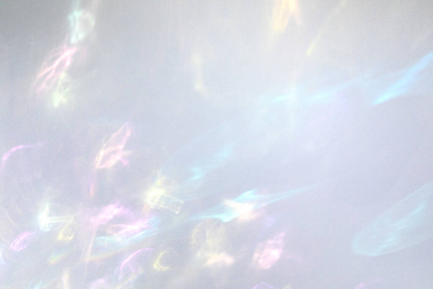 Blurred rainbow light refraction texture overlay effect for photo and mockups. Organic drop diagonal holographic flare on a white wall. Shadows for natural light effects - Photo, Image