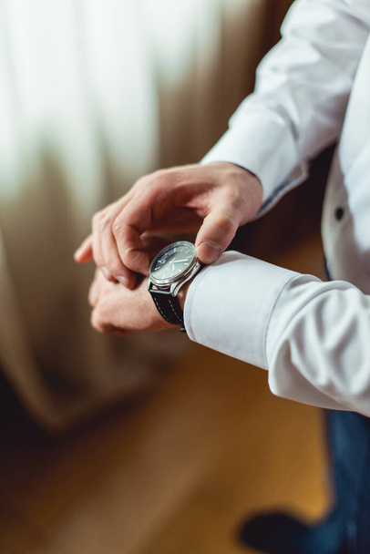homme d'affaires vérifiant l'heure sur sa montre-bracelet, homme mettant horloge sur la main, marié se préparer le matin avant la cérémonie de mariage - Photo, image