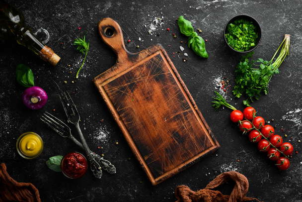 Food background. Kitchen board, vegetables, spices and kitchen utensils on the old table. Free copy space. - Foto, afbeelding