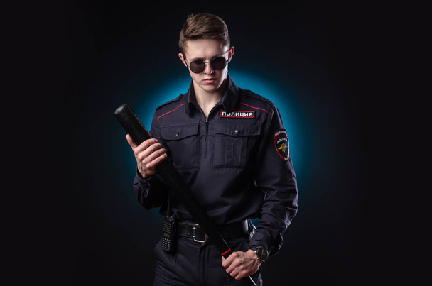 handsome guy in a police officers uniform with a baseball bat. english translation "Police" - Foto, Bild