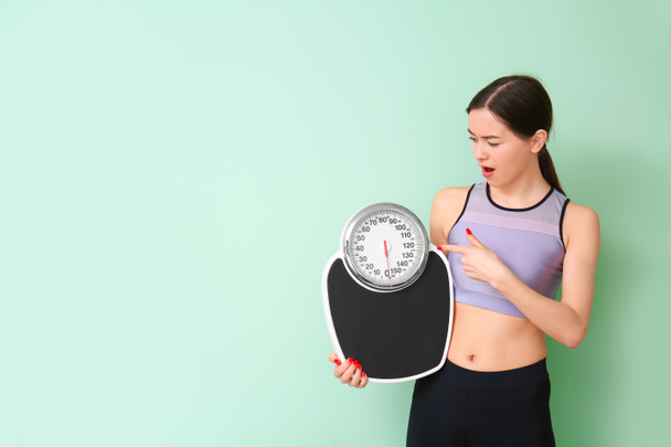 Young woman with weight scales on color background - Photo, Image