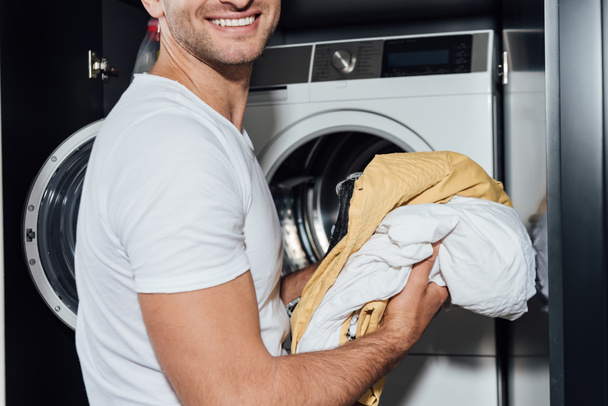 vágott kilátás boldog ember gazdaság piszkos mosás közelében mosógép  - Fotó, kép