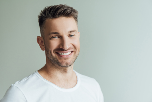 Handsome man smiling while looking at camera isolated on grey  - Photo, Image
