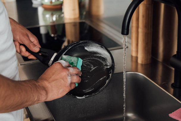 Vágott kilátás az ember tisztító serpenyő a konyhában  - Fotó, kép