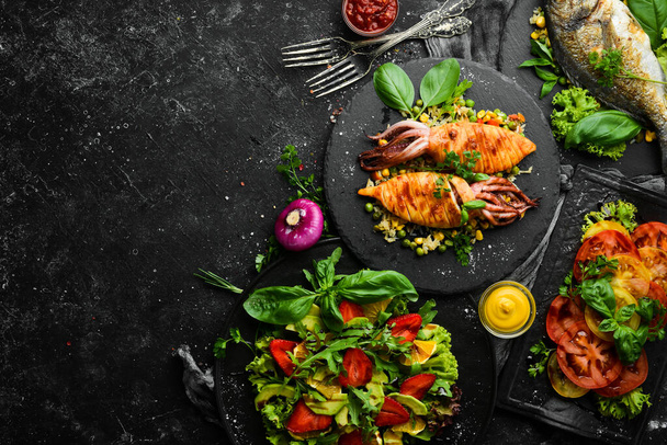 Food background. Set of dishes of fish, meat and vegetables on black stone background. Top view. Free copy space. - 写真・画像