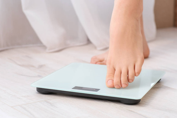 Jovem mulher medindo seu peso em casa, close-up
 - Foto, Imagem