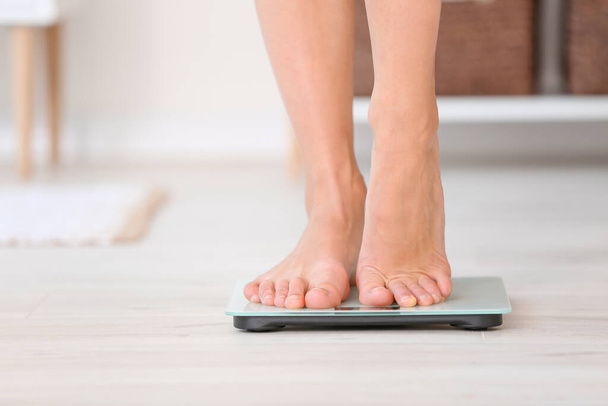 Jonge vrouw meten van haar gewicht thuis - Foto, afbeelding