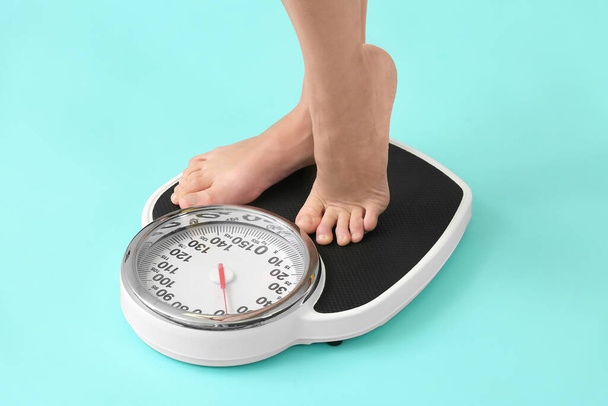 Jovem mulher medindo seu peso sobre fundo de cor
 - Foto, Imagem