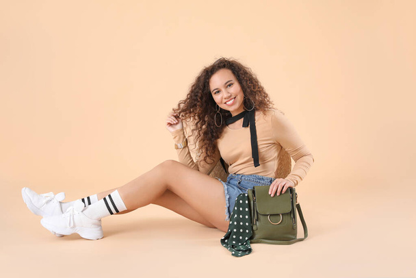 Beautiful young African-American woman with stylish bag on color background - Фото, зображення