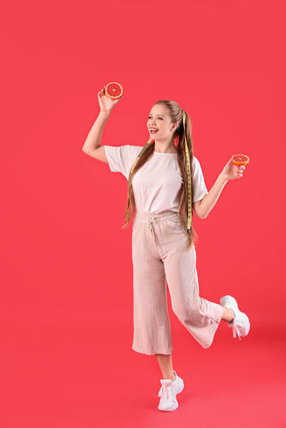 Young woman with grapefruit and measuring tape on color background. Diet concept - Photo, Image