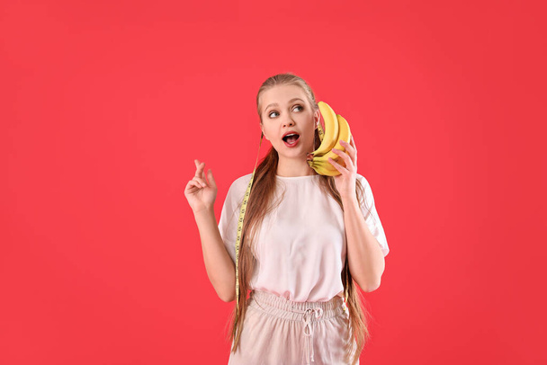 Giovane donna con banane e nastro di misurazione su sfondo a colori. Concetto di dieta - Foto, immagini