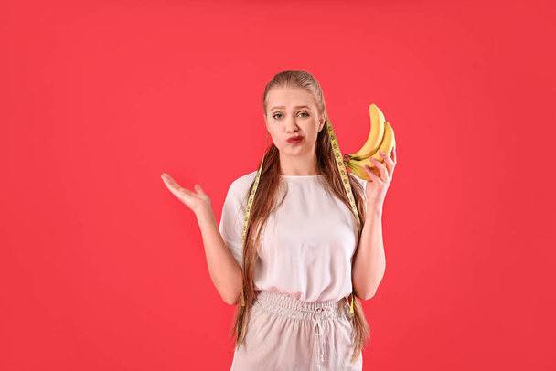 Νεαρή γυναίκα με μπανάνες και μεζούρα στο φόντο του χρώματος. Έννοια διατροφής - Φωτογραφία, εικόνα